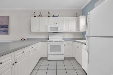Kitchen with white cabinetry, ornamental molding, 
