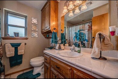 Bathroom with vanity, toilet, tile patterned flooring, baseboards, and a textured wall