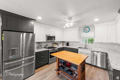 Kitchen featuring appliances with stainless steel finishes, light wood finished floors, white cabinetry, recessed lighting, and a ceiling fan