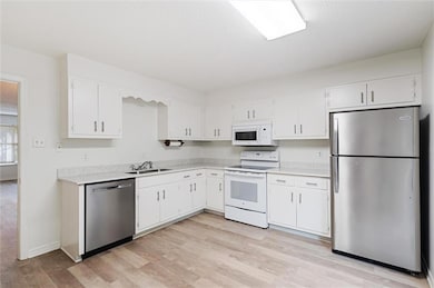 Kitchen with white cabinets, light wood-type flooring, and stainless steel appliances