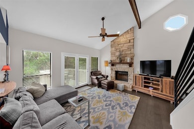 Living room with high vaulted ceiling, a fireplace, beam ceiling, dark wood-style floors, and a ceiling fan