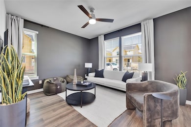 Living area with a ceiling fan, baseboards, and wo