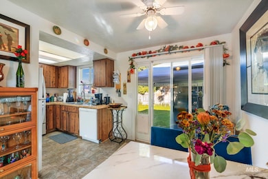 Kitchen featuring brown cabinets, light countertops, white appliances, a ceiling fan, and a textured ceiling