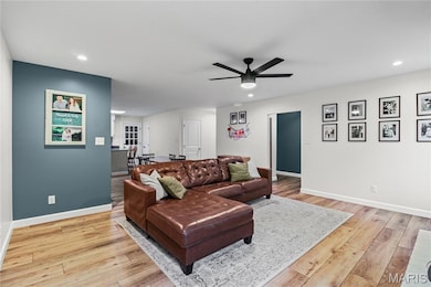 Living room with light wood-type flooring, a ceiling fan, and recessed lighting
