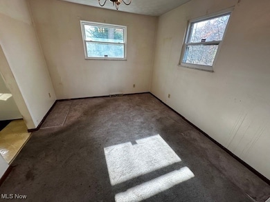 Empty room with plenty of natural light, carpet, and a chandelier
