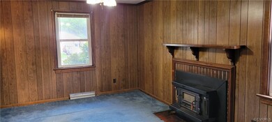 Unfurnished living room with a wood stove, baseboa
