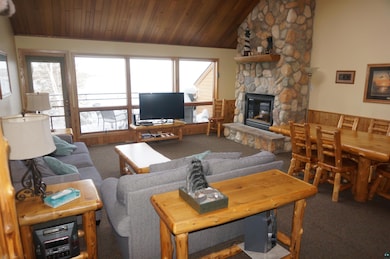 Carpeted living area featuring a stone fireplace, 