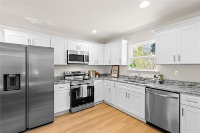 Kitchen with white cabinets, a sink, light wood fi
