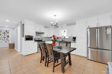 Dining area featuring light tile patterned floors, recessed lighting, and a chandelier
