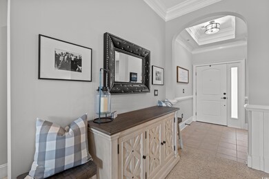 Foyer entrance with a tray ceiling, arched walkways, crown molding, and light tile patterned flooring