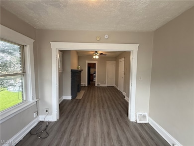 Spare room with wood finished floors, healthy amount of natural light, and a textured ceiling