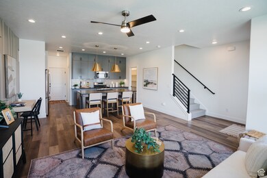 Living room featuring stairs, dark wood-style flooring, ceiling fan, and recessed lighting