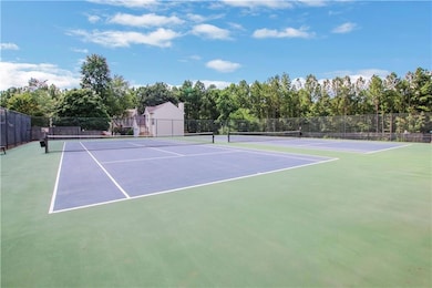 View of tennis court with community basketball court and view of scattered trees