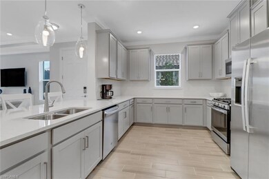 Kitchen featuring gray cabinets, a sink, ornamental molding, and appliances with stainless steel finishes