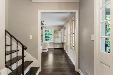 Entrance foyer with dark wood-style flooring, ornamental molding, stairs, and baseboards
