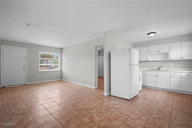 Kitchen with white appliances, light tile patterned floors, light countertops, and white cabinetry