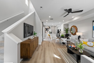 Living area with stairway, a ceiling fan, light wood-style floors, and recessed lighting