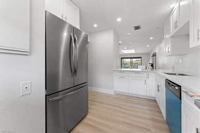 Kitchen with freestanding refrigerator, dishwashing machine, recessed lighting, white cabinetry, and light wood-type flooring