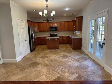 Kitchen with backsplash, a center island, light countertops, a chandelier, and decorative light fixtures