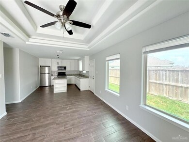 Unfurnished living room featuring a raised ceiling, wood tiled floors, and a ceiling fan