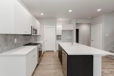 Kitchen featuring white cabinetry, appliances with stainless steel finishes, light wood-type flooring, decorative backsplash, and recessed lighting
