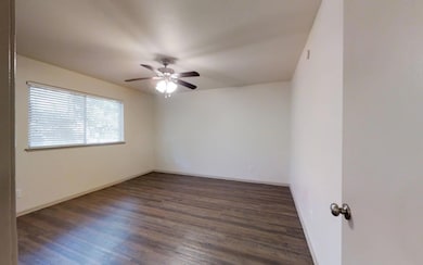 Unfurnished room featuring ceiling fan and dark wo