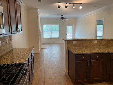 Kitchen with a healthy amount of sunlight, tasteful backsplash, ceiling fan, and light wood-style floors