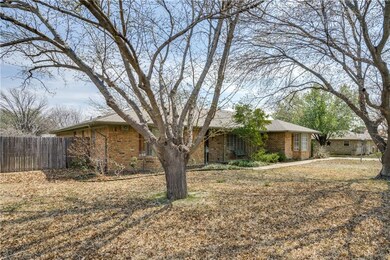 View of front yard with mature trees and landscapi