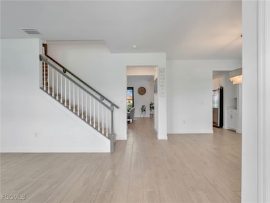 Foyer entrance with light wood-style tile flooring and stairs