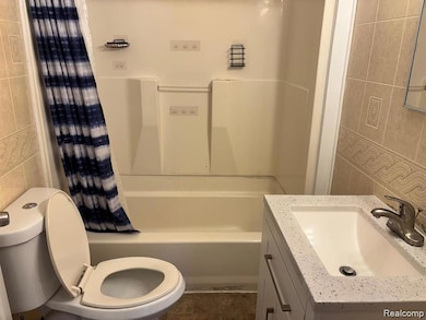 Bathroom with tile walls, shower / tub combo, vanity, and dark tile patterned floors
