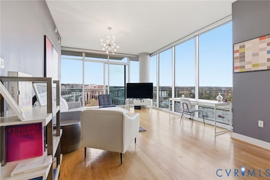 Living room with floor to ceiling windows, light wood finished floors, and a chandelier