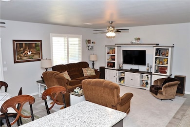 Tiled living area with ceiling fan and baseboards