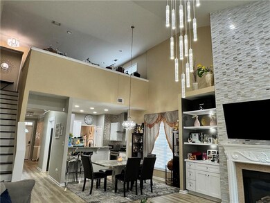 Dining room featuring light wood-style floors, stairway, a towering ceiling, a tile fireplace, and a chandelier