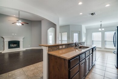 Kitchen featuring light tile patterned flooring, appliances with stainless steel finishes, pendant lighting, sink, and a kitchen island with sink