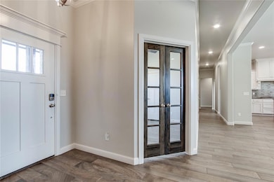 Entryway featuring light wood-style floors, crown molding, and recessed lighting