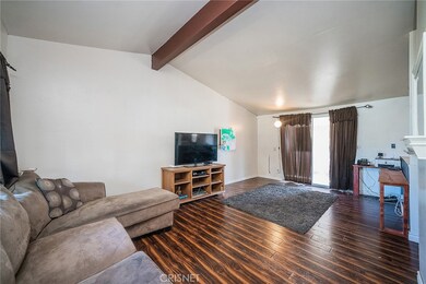 Living room adjacent dining area with glass sliding door leading to enclosed patio.  Newer wood laminate flooring