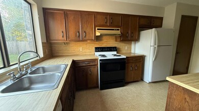 Kitchen with range with electric cooktop, freestanding refrigerator, light countertops, range hood, and decorative backsplash