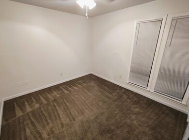 Unfurnished room with dark carpet, ceiling fan, and baseboards