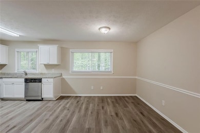 Kitchen featuring dishwasher, a textured ceiling, white cabinets, and a sink