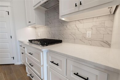 Kitchen with backsplash, range hood, white cabinet