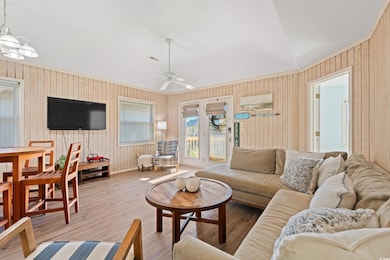 Living room featuring wooden walls, ceiling fan wi