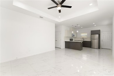 Unfurnished living room featuring a sink, visible vents, a raised ceiling, and marble finish floor