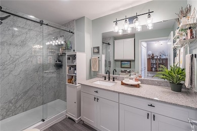 Full bath featuring a shower stall, vanity, and wood finished floors