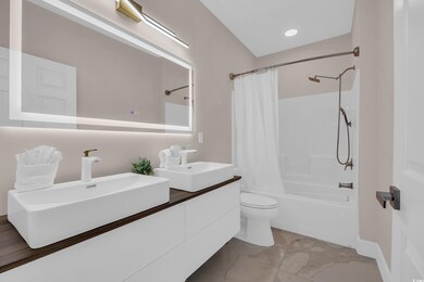 Full bathroom featuring shower / bathtub combination with curtain, double vanity, light marble finish flooring, and recessed lighting