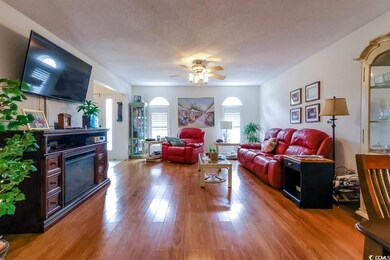 Living room featuring arched walkways, wood finished floors, a ceiling fan, and a fireplace