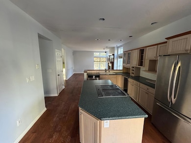 Kitchen with dark countertops, dark wood finished floors, a sink, dishwashing machine, and freestanding refrigerator