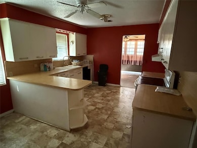 Kitchen featuring light countertops, a peninsula, stainless steel electric range, and white cabinetry