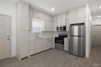 Kitchen with appliances with stainless steel finishes, light wood-style floors, white cabinets, and recessed lighting