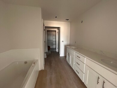 Bathroom with double vanity, a bath, and dark wood-style floors