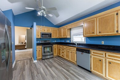 Kitchen featuring light wood finished floors, vaulted ceiling, appliances with stainless steel finishes, a ceiling fan, and a sink